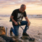 Man using a metal detector on a beach at sunset