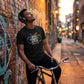 Man with headphones leaning against a graffiti-covered wall with a bicycle.